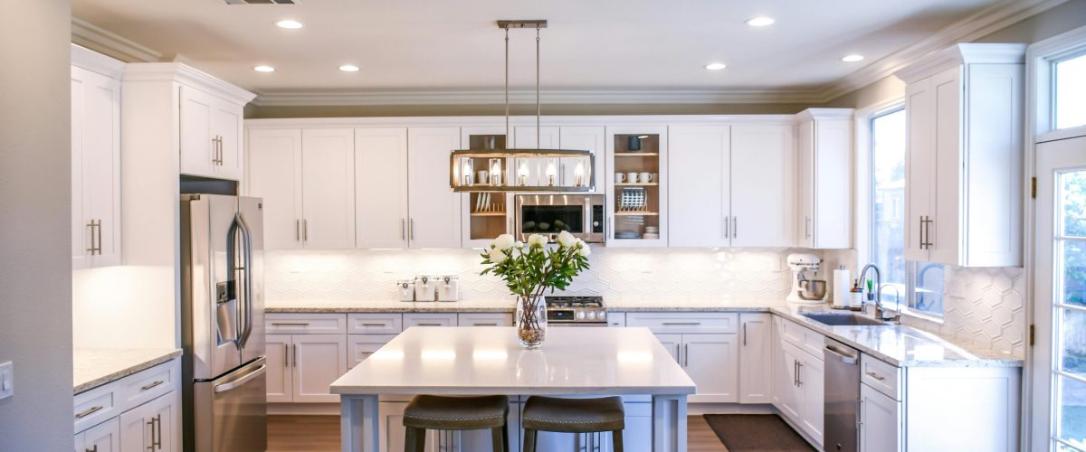 Spacious and elegant kitchen featuring white cabinetry, island, and stainless steel appliances.